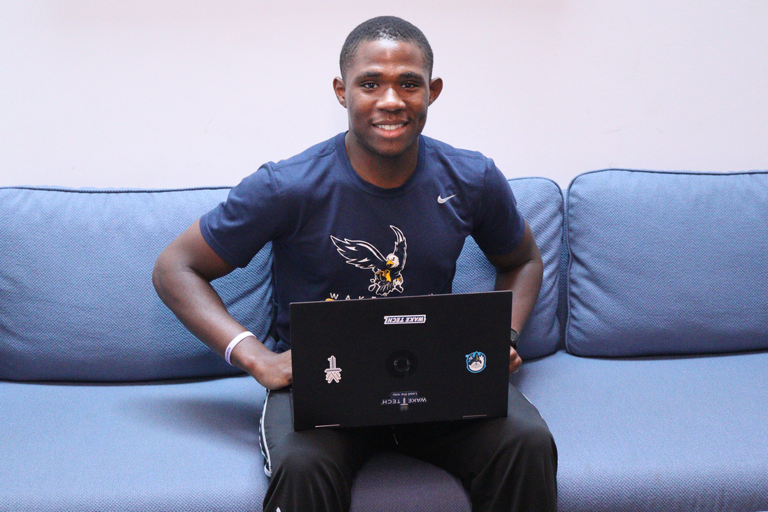 male smiling while sitting on the couch and using a laptop